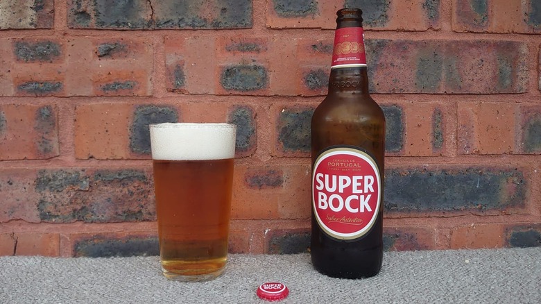 A bottle of Super Bock lager next to a full glass with the bottle cap displayed in front