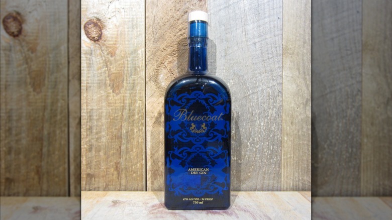 A bottle of Bluecoat American Dry Gin against wood backdrop.