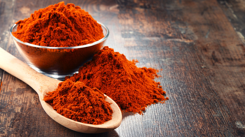 Cayenne pepper in glass bowl and on wooden spoon