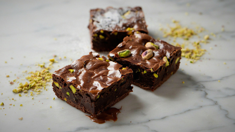 Three pistachio brownies on marble surface