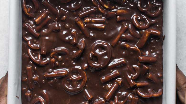 Brownie batter in baking pan with pretzel pieces