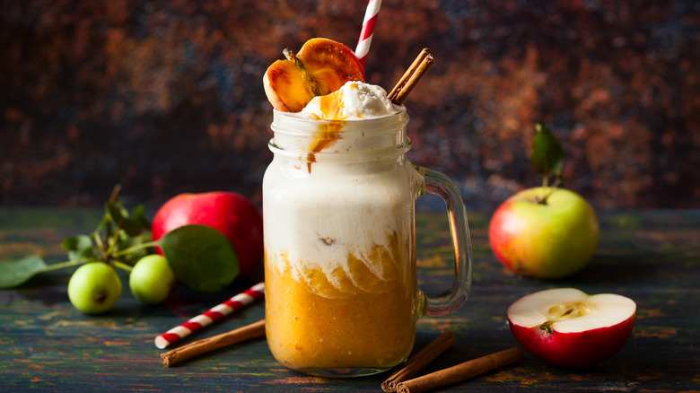 Apple cider float topped with shipped cream, caramel sauce, cinnamon stick, and apple