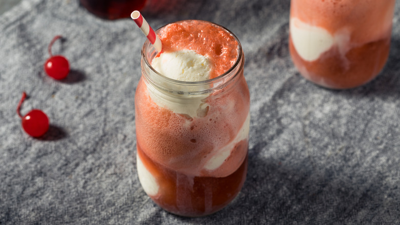 Cherry cola ice cream float in glass with straw