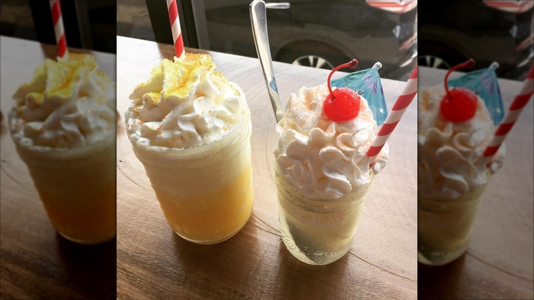 Two glasses of pina colada floats topped with whipped cream