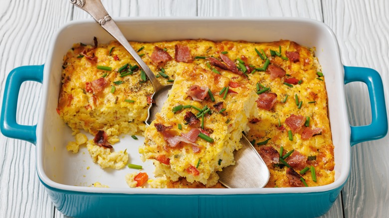 Corn casserole in a blue casserole dish with silver spoon
