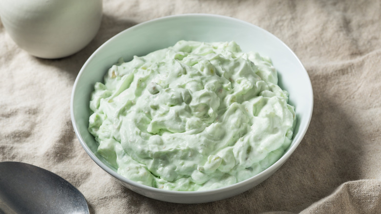 Green Watergate Salad in a white bowl on a beige tablecloth