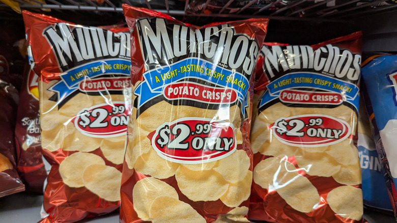 Three bags of Munchos potato crisps on a shelf.