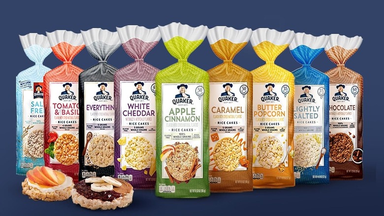 A lineup of various Quaker Oats rice cakes. From left to right: salt free, tomato & basil, everything, white cheddar, apple cinnamon, caramel, butter popcorn, lightly salted, and chocolate.