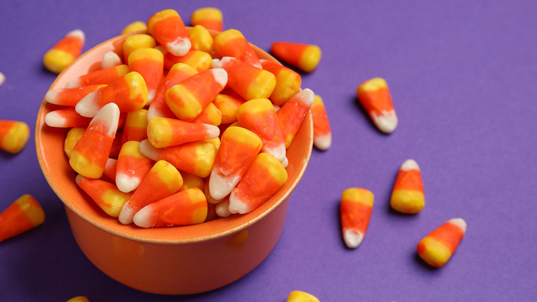 Bowl of candy corns on purple background