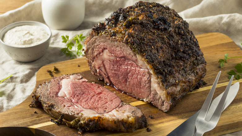 Prime rib roast sliced on wooden board
