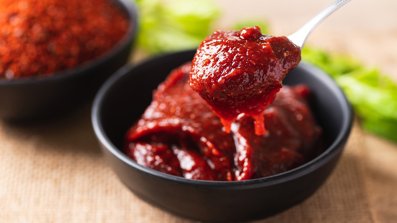Gochujang in a black bowl and on a silver spoon