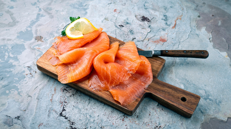 Smoked salmon on a wooden cutting with a knife and lemon