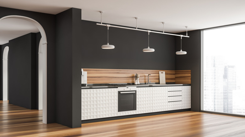 An open kitchen with black walls, wooden backsplash, and white lower cabinets