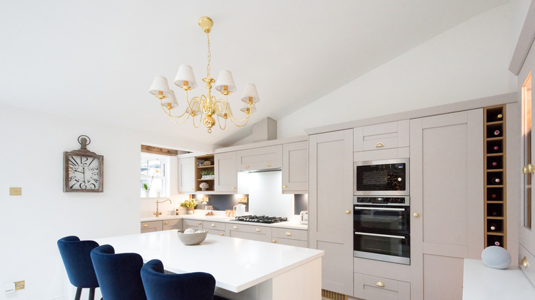 White kitchen with blue chairs and a golden chandelier