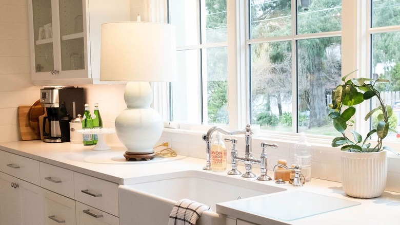 All-white kitchen with a large white lamp next to the farmhouse sink