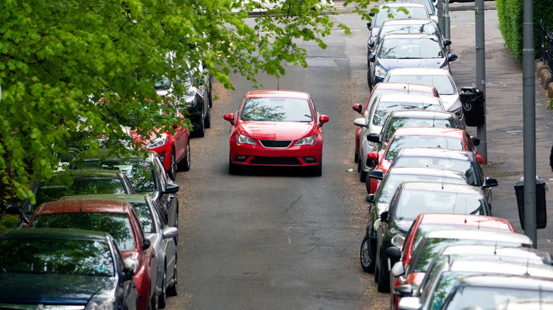 Car driving down a street with no parking spots available.