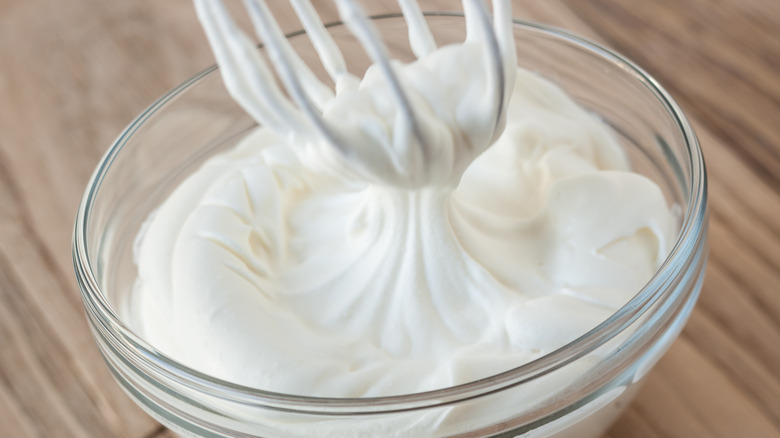 Whisking whipped cream in glass mixing bowl