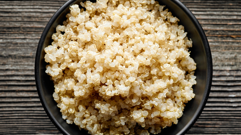 Fluffy cooked quinoa in black bowl