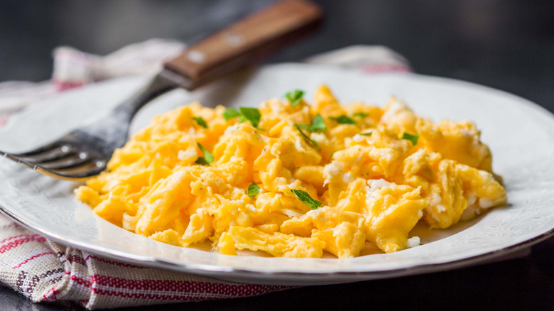Plate of scrambled eggs topped with chopped herbs