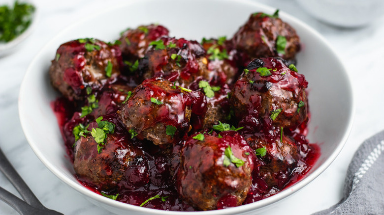 Cranberry-glazed meatballs in bowl with fresh parsley garnish