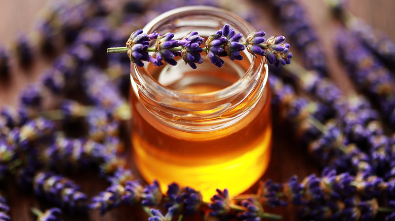 A jar of honey surrounded by lavendar flowers