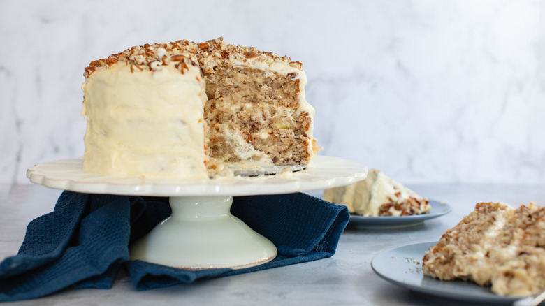 Hummingbird cake on a stand near two slices on plates