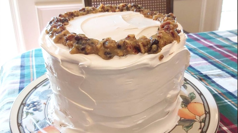 Lane cake topped with fruit mix on a tartan tablecloth