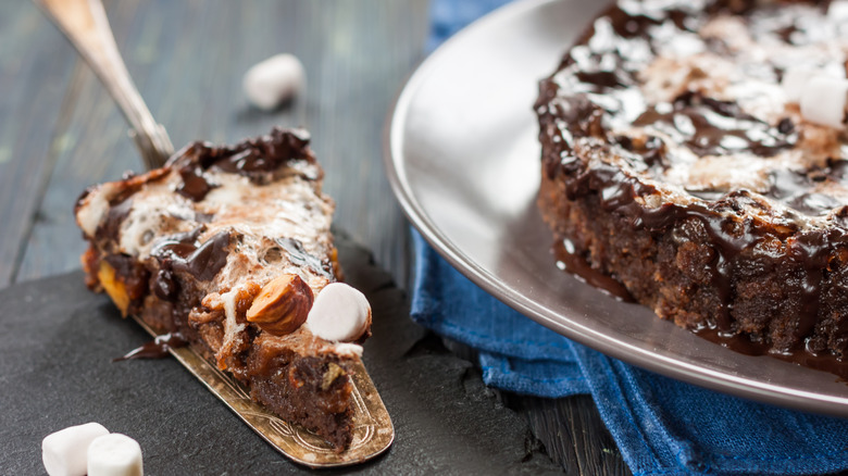 Slice of Mississippi mud pie on a metal spatula next to a whole cake