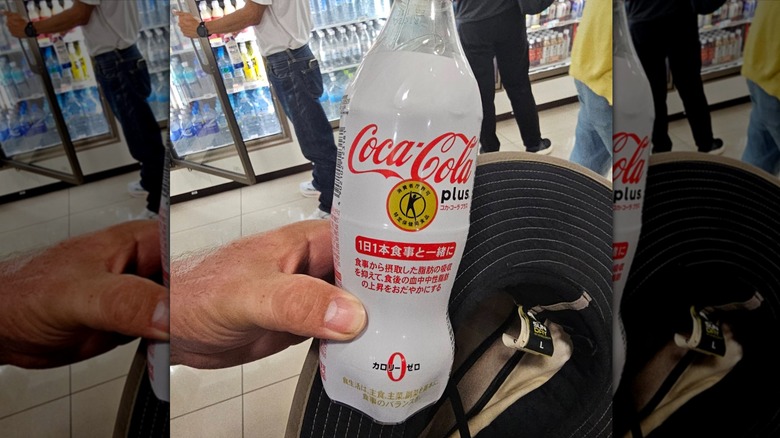 Hand holding a bottle of Coca-Cola Plus at a store