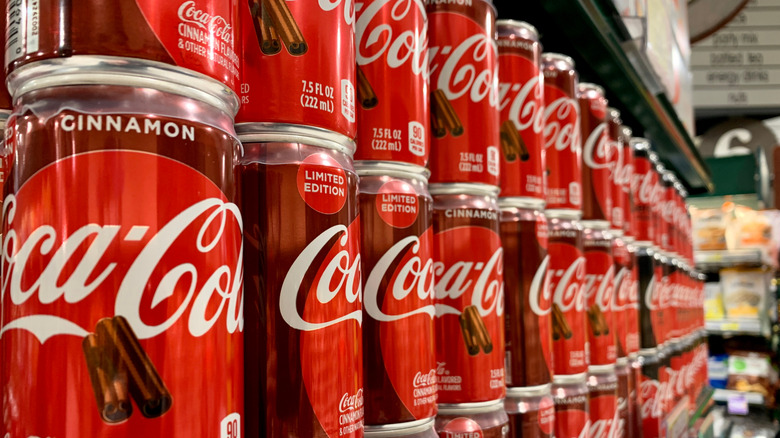 Cans of Coca-Cola Zero Sugar Cinnamon on a store shelf