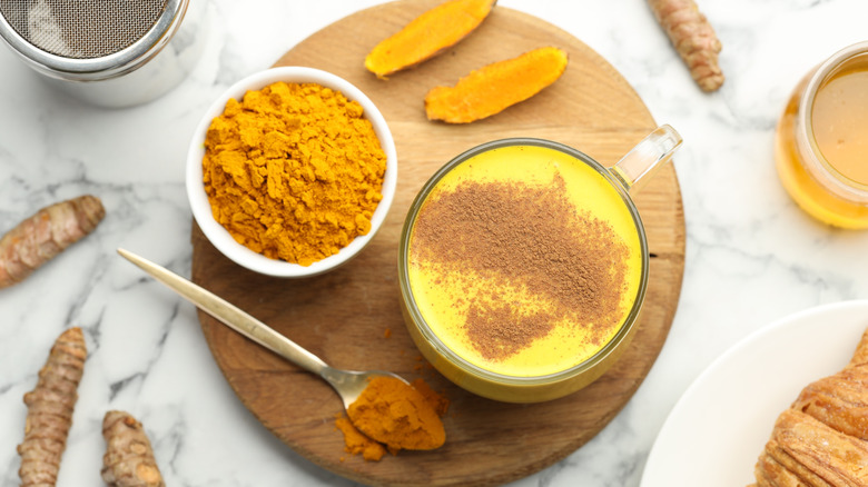 Turmeric latte with powder on wood tray