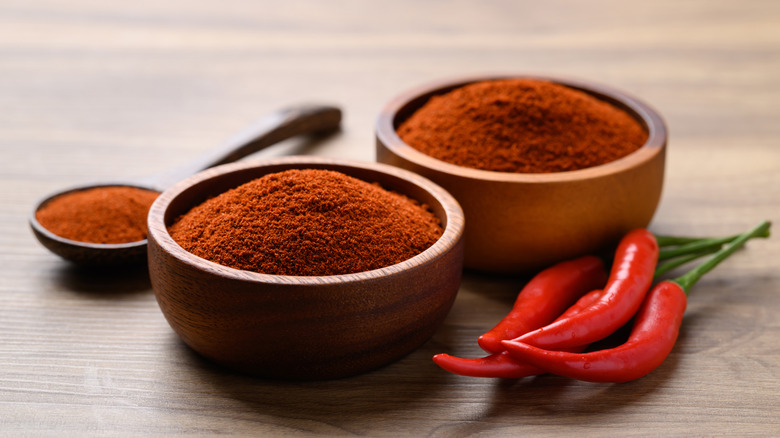 Cayenne pepper in a bowl with fresh peppers