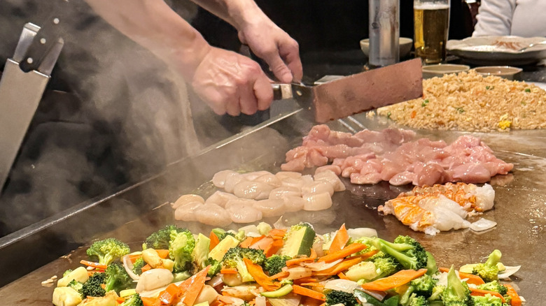 Hibachi chef with metal spatulas cooking food