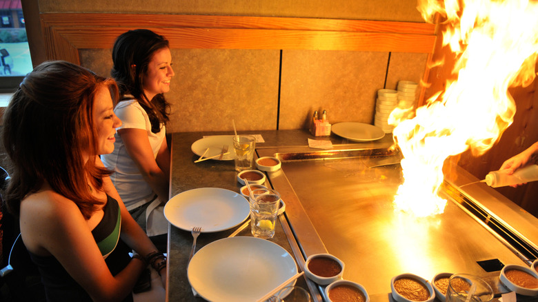 Two young women enjoying the hibachi experience with large flame on grill