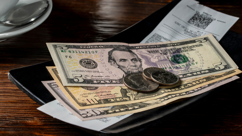Tipping at a restaurant with a pile of cash