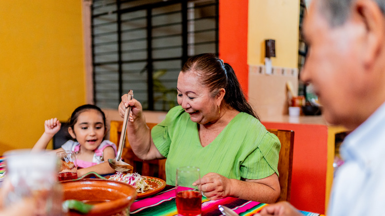 Senior woman serving food with her family