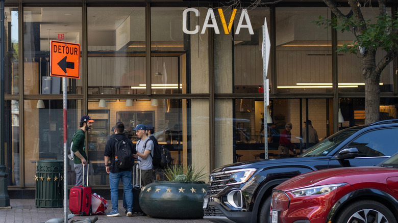People and cars outside of a Cava restaurant
