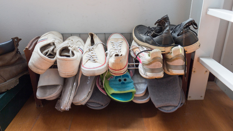 Various shoes arranged messily on shoe rack
