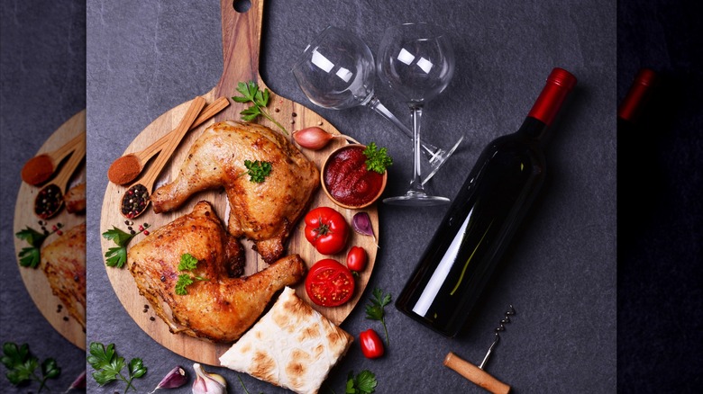 chicken drumsticks on cutting board with red wine bottle