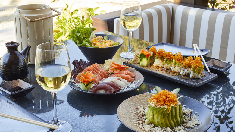 sushi meal on table with white wine glasses