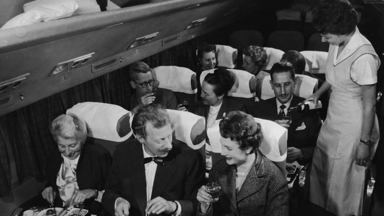 a black and white photo featuing airplane passengers in suits