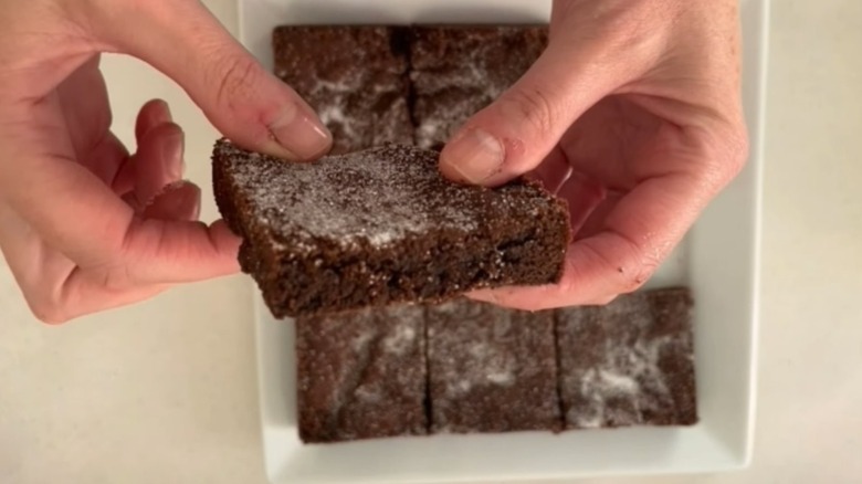 Hands holding piece of chocolate concrete cake