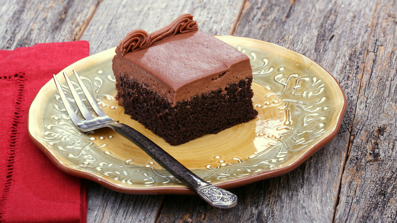 Square of frosted chocolate cake on vintage-style plate