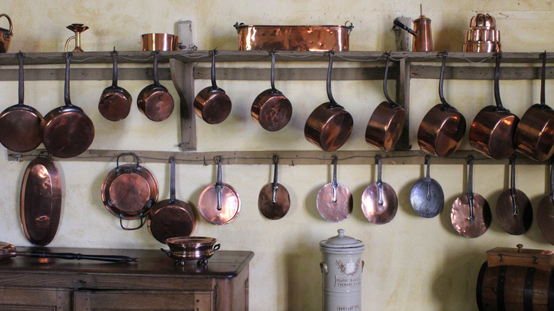 copper pots and pans hanging on a wall