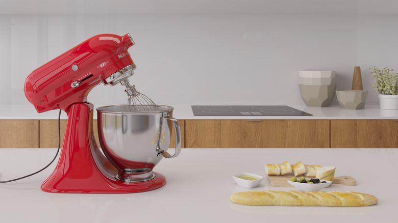 a red kitchenaid mixer on a counter with food