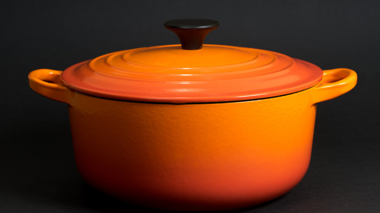 a red-orange dutch oven on a black background