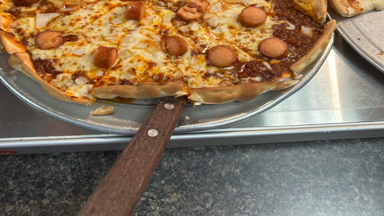 Cheesy pizza topped with sliced hot dog sausages