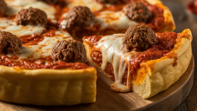 Sliced deep dish pizza topped with meatballs