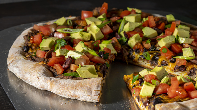 Taco-style pizza with diced avocado and tomatoes