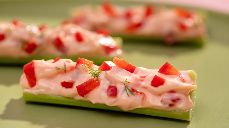 Celery sticks stuffed with cream cheese and diced red peppers